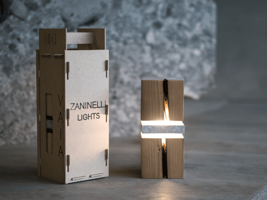 Vaia lampada con imballaggio Lampada da comodino sulla destra in legno e pietra e inballaggio sulla sinistra.